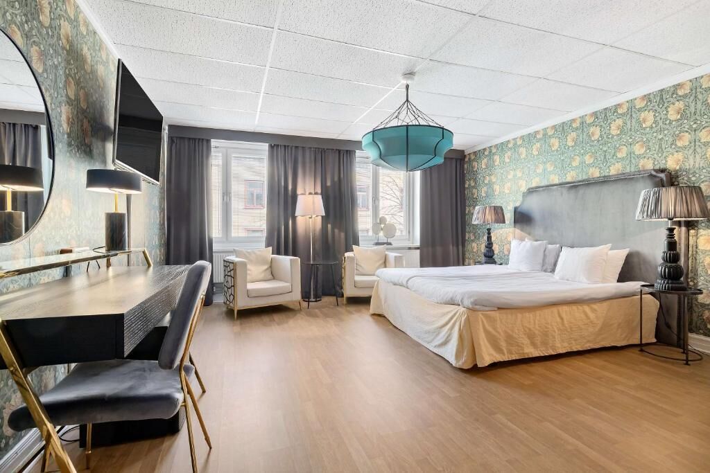 Una habitación de hotel moderna con una cama grande, un escritorio con silla, un sofá y una televisión.