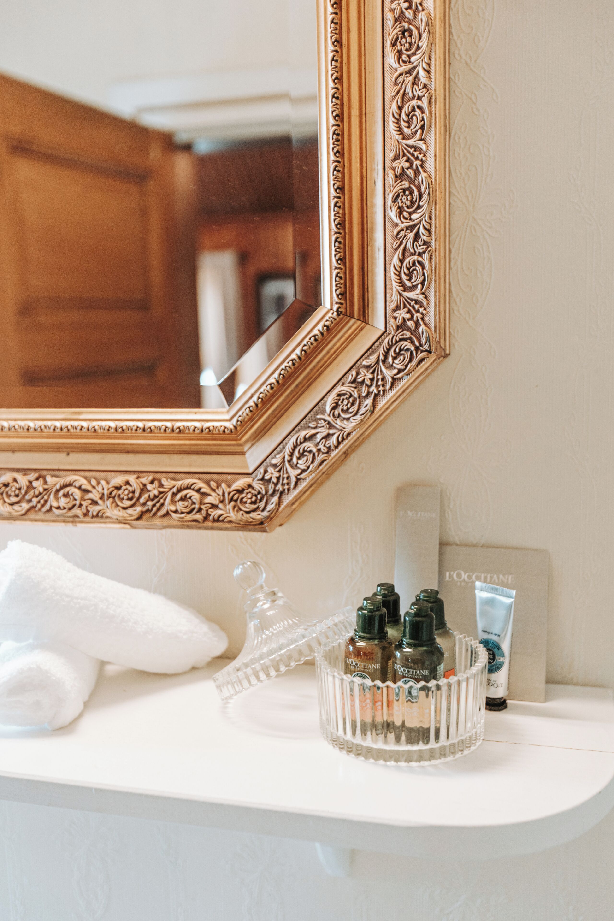 A bathroom vanity with a mirror, toiletries, and a towel.