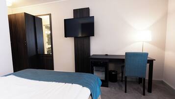 Een hotelkamer met een bed, een bureau, een stoel, een televisie en een lamp.