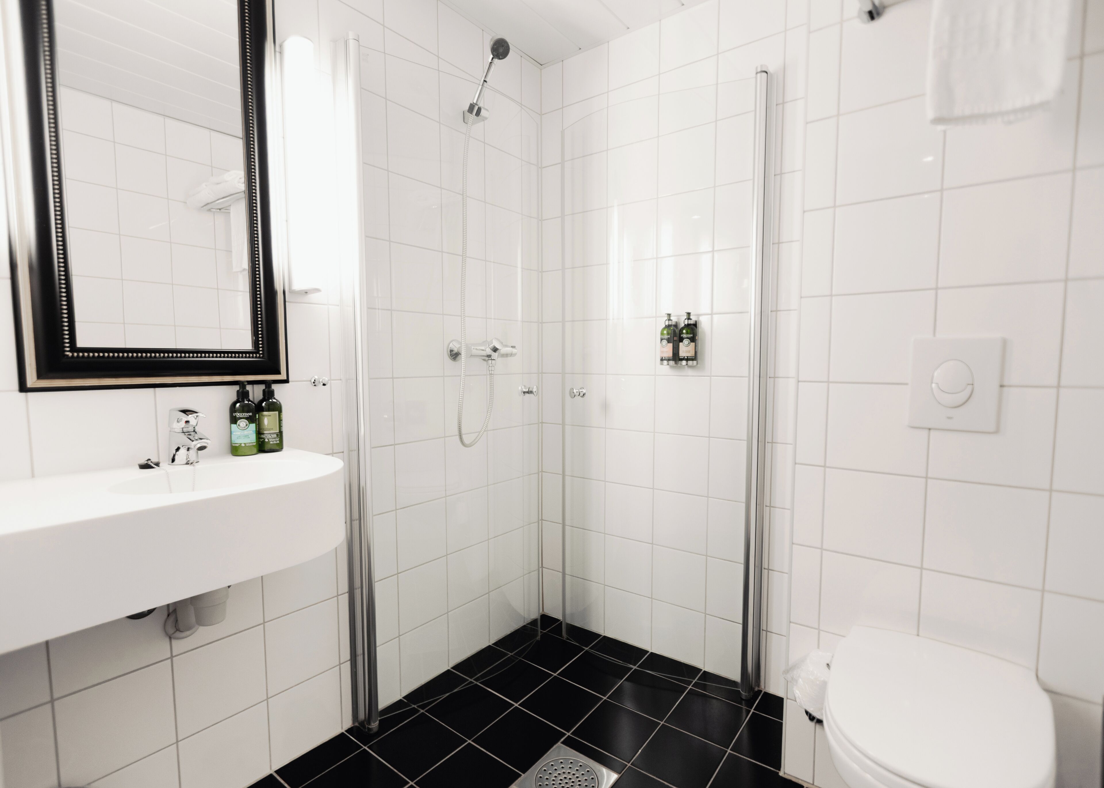 Un baño con un lavabo blanco, un espejo, ducha y retrete.