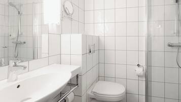 A modern bathroom with a white sink, toilet, and shower.