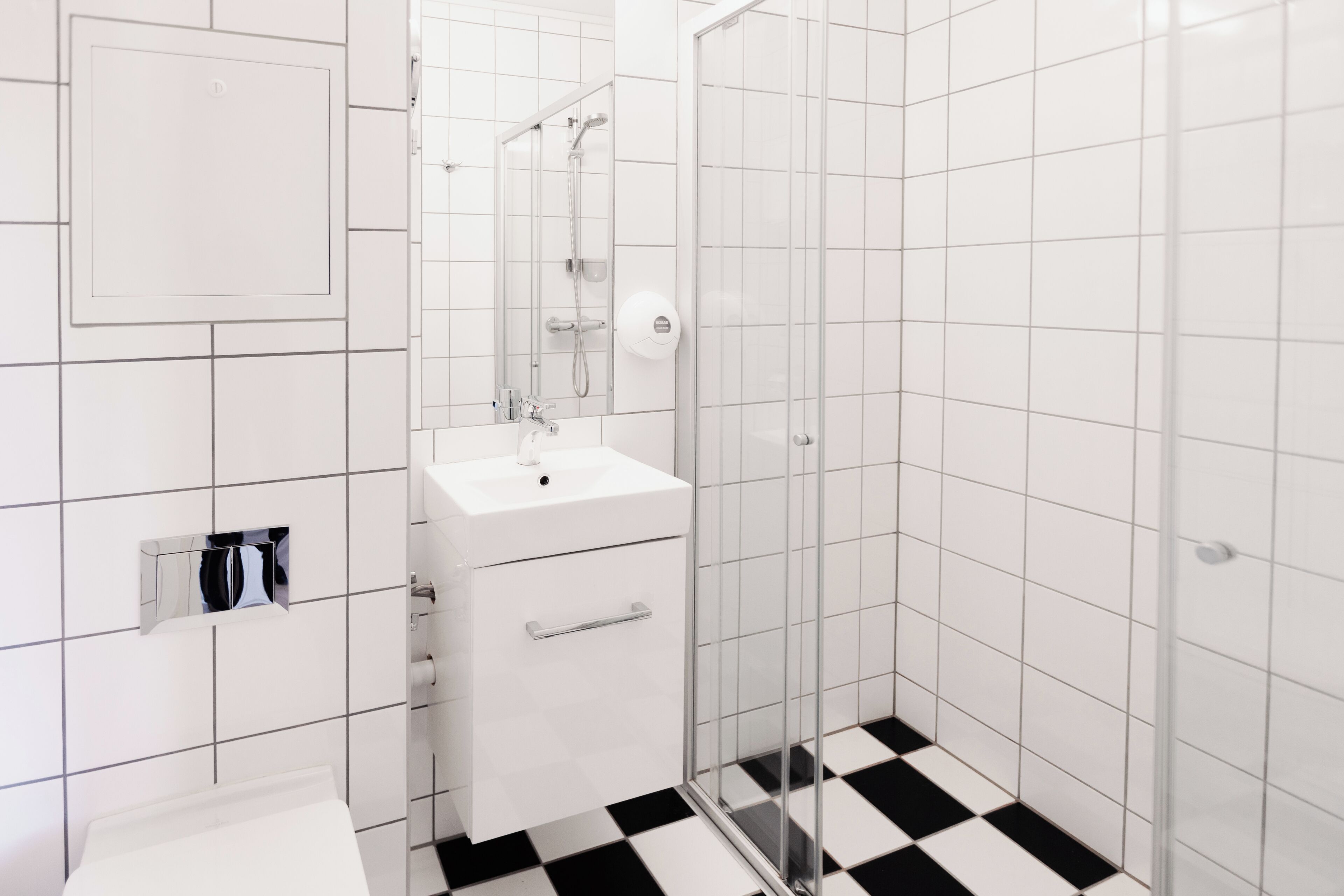 A modern bathroom with a white sink, mirror, and glass shower enclosure.