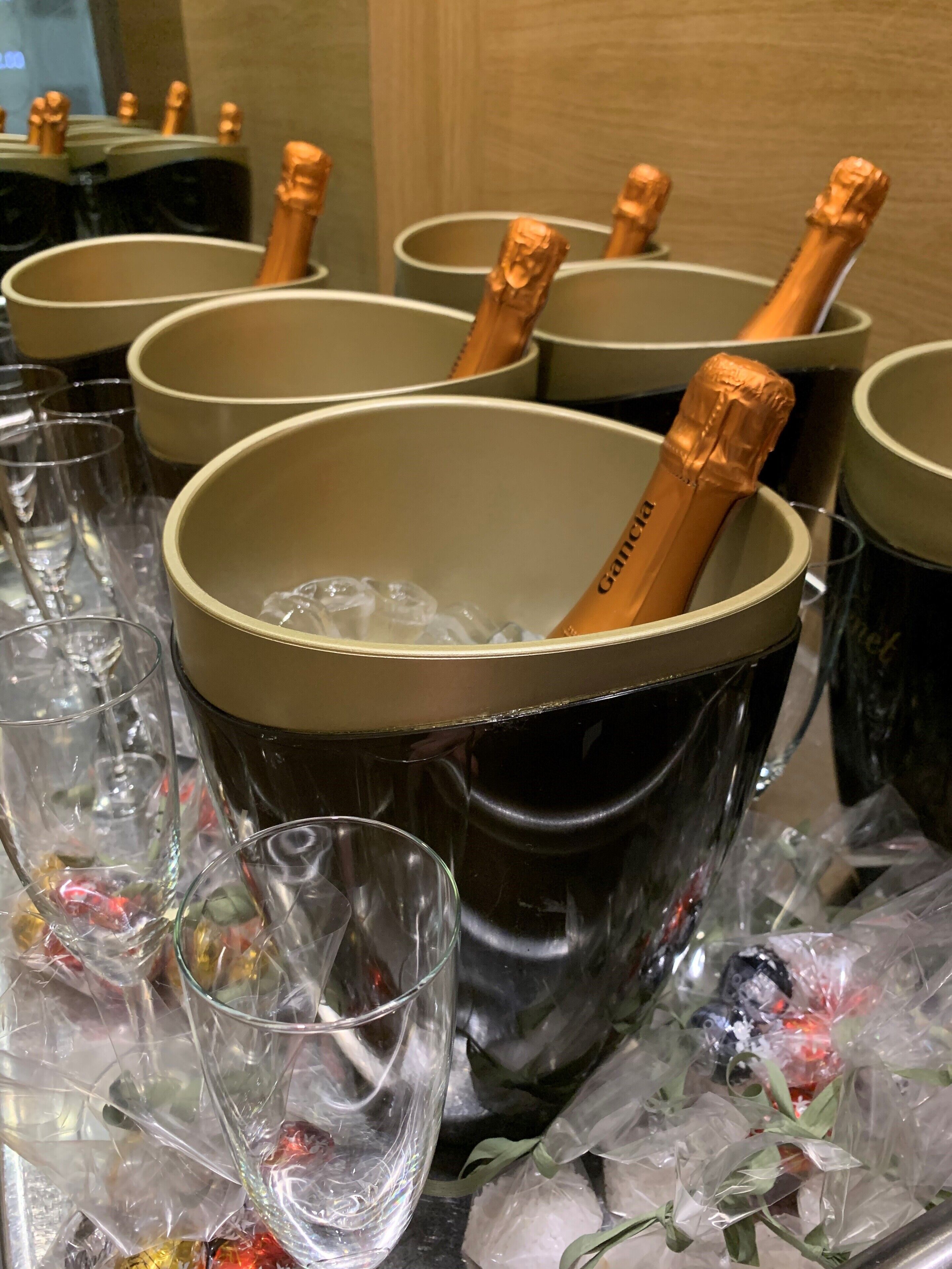 Un balde con copas de champán y botellas de champán, rodeado de copas vacías y hielo.