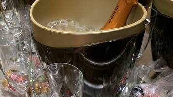 Un balde con copas de champán y botellas de champán, rodeado de copas vacías y hielo.