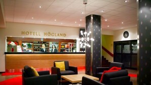 A hotel lobby with a reception desk, seating area, and a staircase.