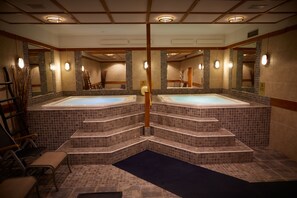 Un área de spa con dos jacuzzis, paredes con azulejos y un banco de madera.