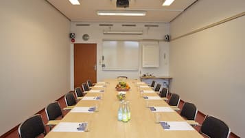 A conference room with a long table, chairs, a projector, and a whiteboard.