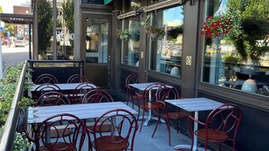 A restaurant with outdoor seating, including tables and chairs, and a green awning with the name "ABRO".