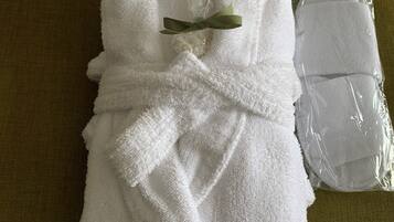 A neatly folded white towel with a green leaf decoration, placed on a green pillow with a striped pattern.