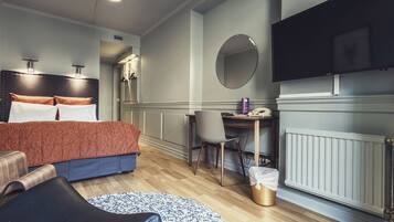 Una habitación de hotel moderna con cama, escritorio, silla, televisor y radiador.