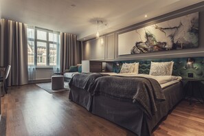 A modern hotel room with a large bed, a desk, and a view of the city through large windows. - Hotel Poseidon (Gothenburg)