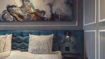 Een slaapkamer met een gestuwd hoofdeinde, een bed met witte lakens en een wandgemonteerde koffiezetapparaat.