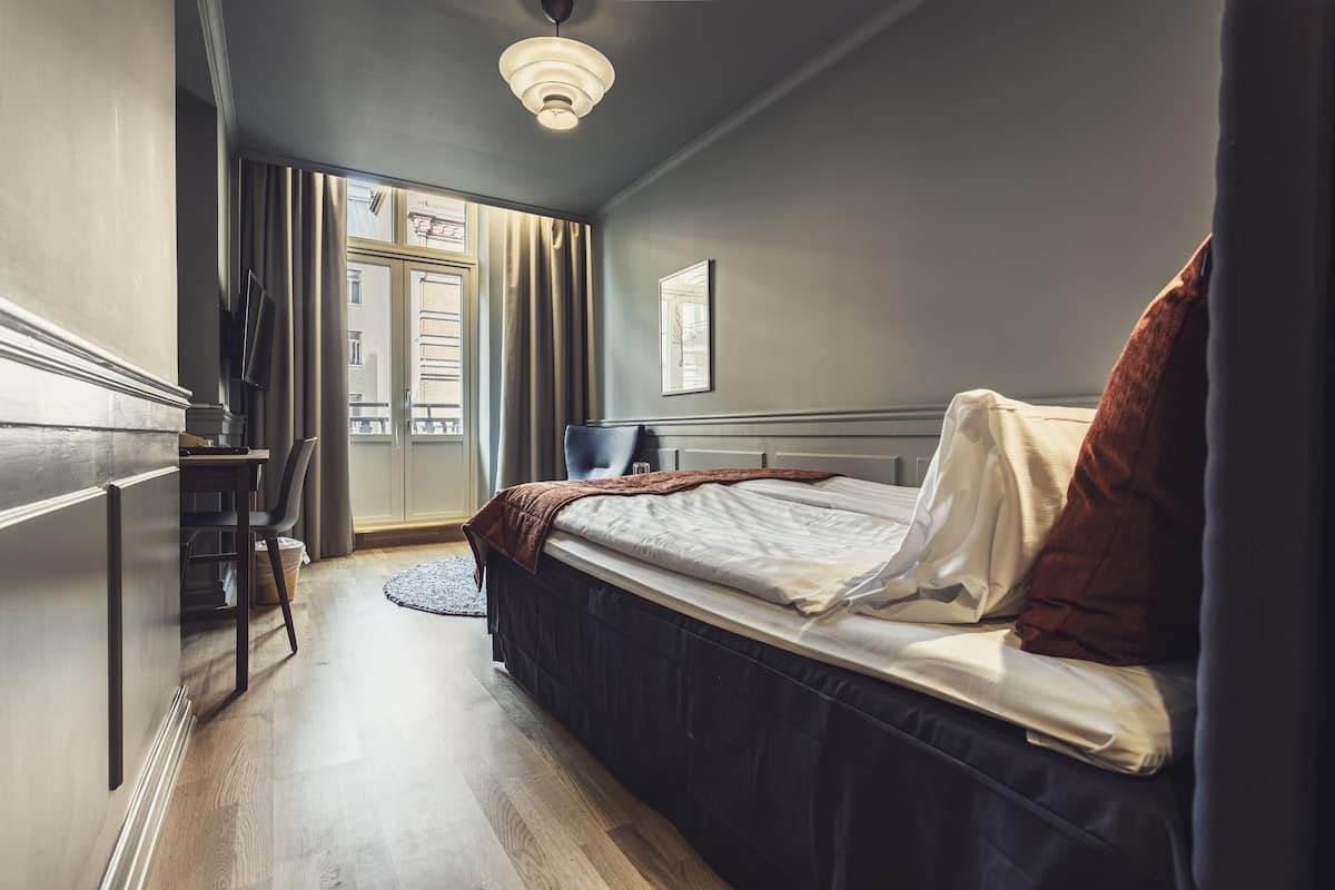 A bedroom with a bed, a desk, and a chair.