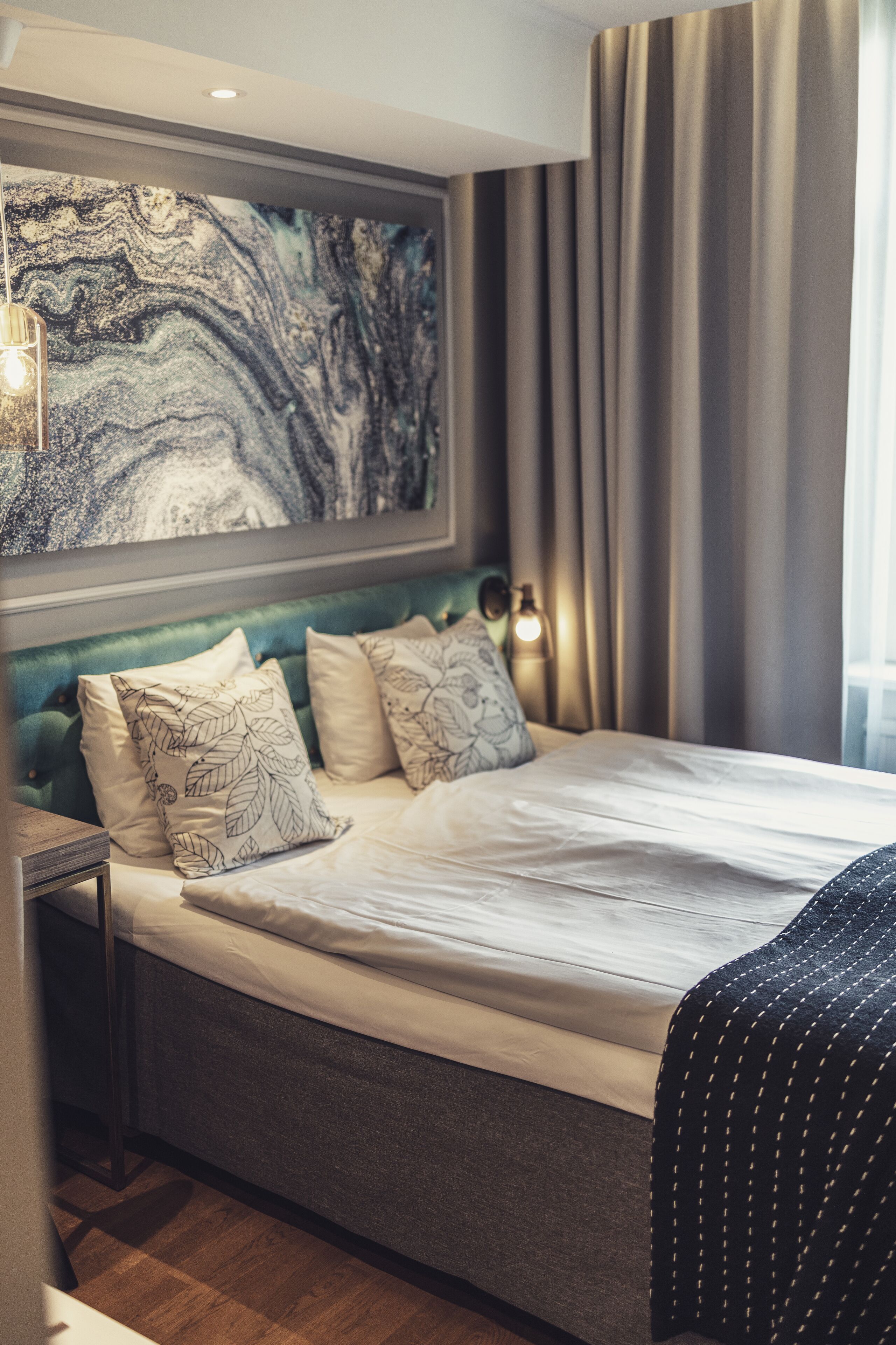 Un dormitorio moderno con una cama grande, un cabecero con motivos de hojas y una obra de arte colgada en la pared.