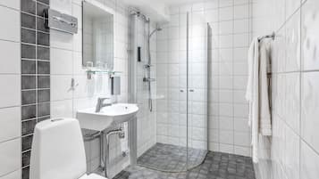 Un baño moderno con lavamanos, espejo y ducha blancos.