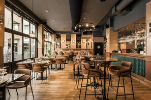A restaurant with multiple dining tables and chairs, a bar area, and large windows allowing natural light. - Comfort Hotel Linköping City (Linkoping)