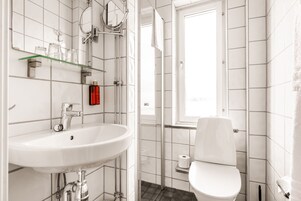 Un baño moderno con lavamanos, espejo y retrete blancos.