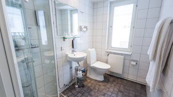 A modern bathroom with a glass shower enclosure, a white sink, and a toilet.