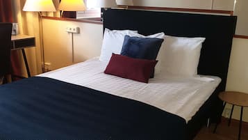 Habitación de hotel con cama, dos lámparas de noche, un televisor en la pared y una mesita.