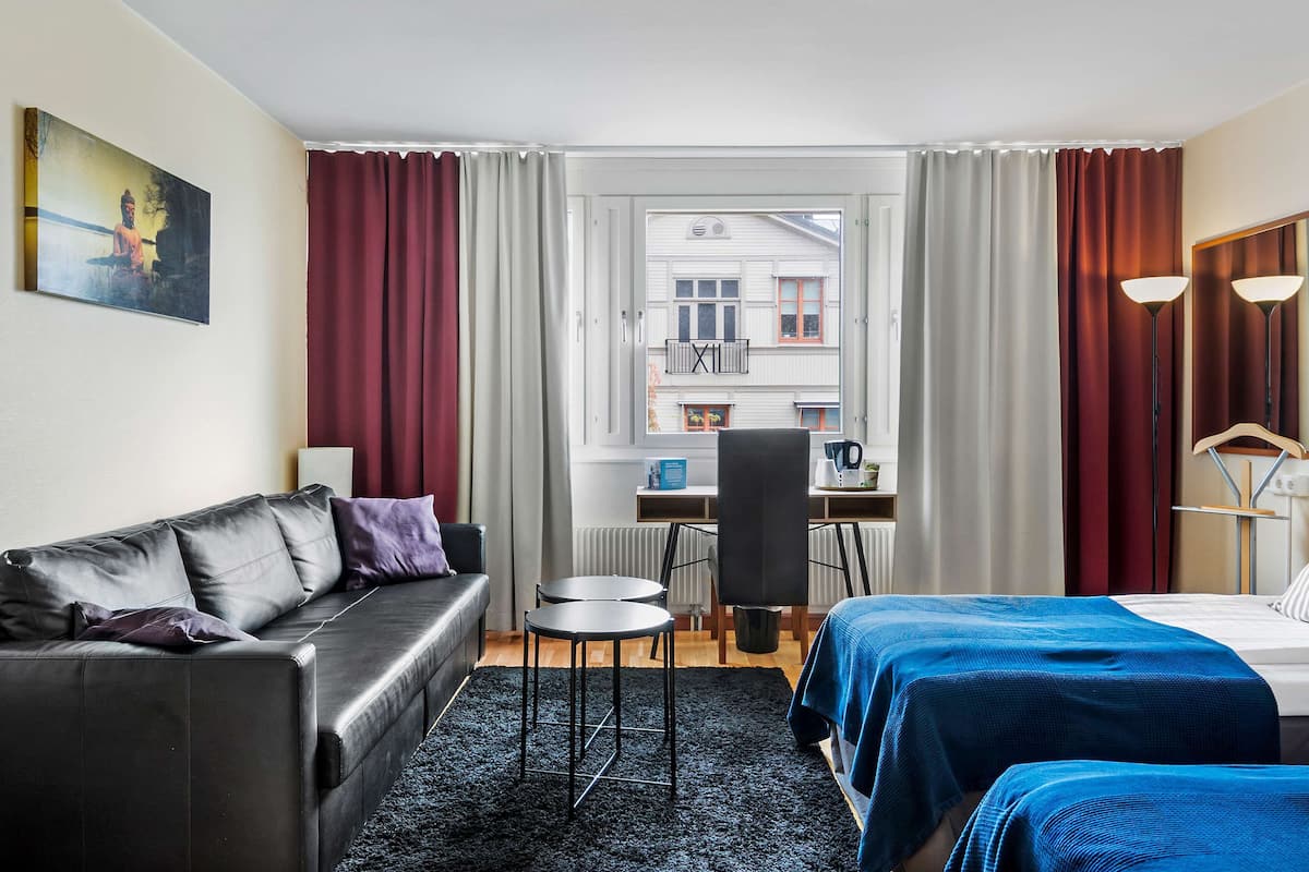 Une chambre d’hôtel avec un lit, un canapé, un bureau et une chaise.