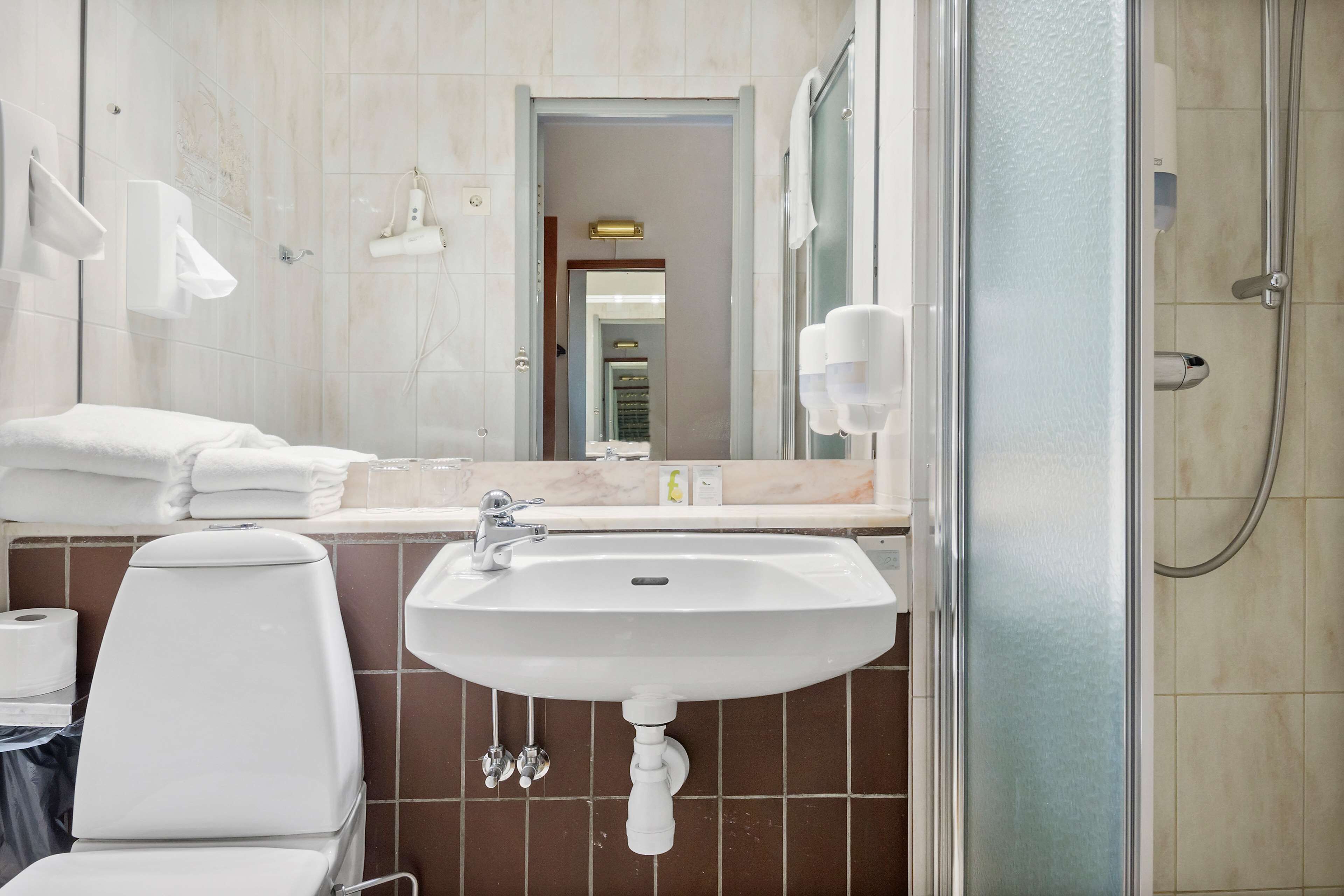 A bathroom with a sink, mirror, and shower.