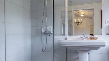 A modern bathroom with a glass-enclosed shower, a white pedestal sink, and a large mirror.