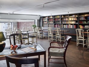 A spacious library with a large collection of bookshelves, comfortable seating, and a dining area with a glass table and chairs. - Hotel Vasa, BW Signature Collection (Gothenburg)