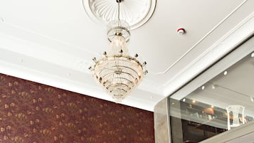 Een restaurant met een hoge plafond, een kroonluchter en een patroonwand.
