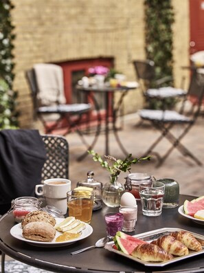 An outdoor dining area with tables, chairs, and a variety of food and drink items. - Hotel Vasa, BW Signature Collection (Gothenburg)