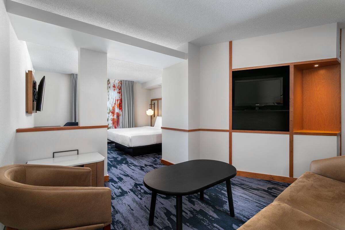 A hotel room with a bed, a desk, a TV, and a sofa.