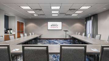 Une salle de conférence avec une longue table, des chaises et une banderole sur laquelle on peut lire : « Événements Marriott Bonvoy ».