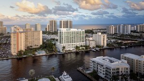 Un hôtel de grande hauteur au design moderne, situé près d’un front de mer avec un port de plaisance.