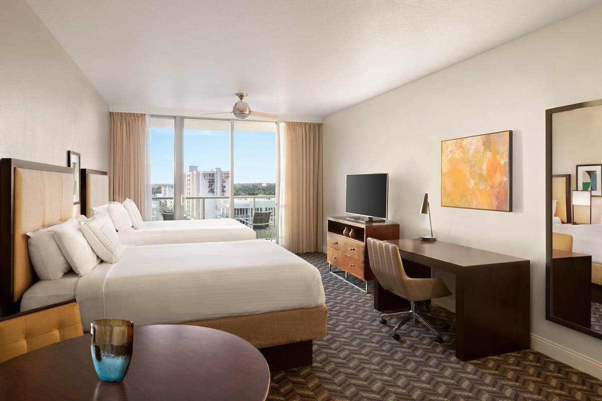 Habitación de hotel con una cama grande, un escritorio, un televisor y vistas de la ciudad.