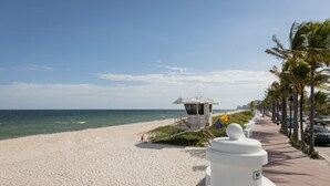 Une plage avec une tour de surveillance, des palmiers et un ciel dégagé.