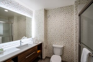 Bathroom features a large mirror, sink, and toilet, with a geometric pattern on the walls.