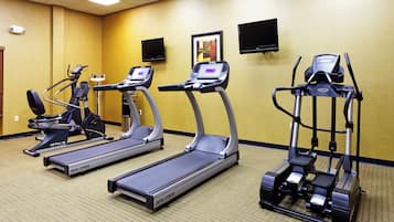 A fitness room with three treadmills, a stationary bike, and a rowing machine.