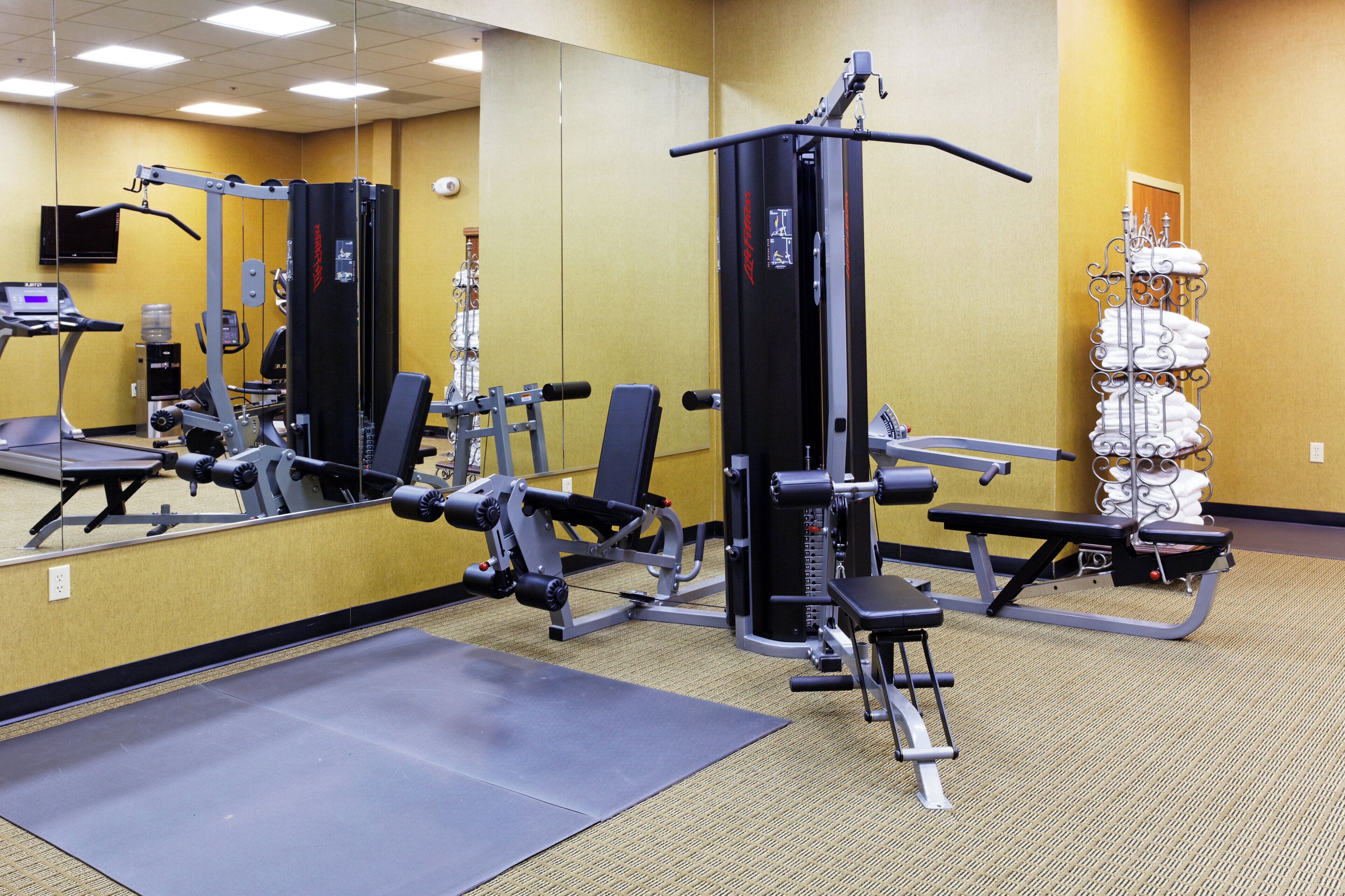 A gym with various exercise equipment, a water dispenser, and a towel rack.