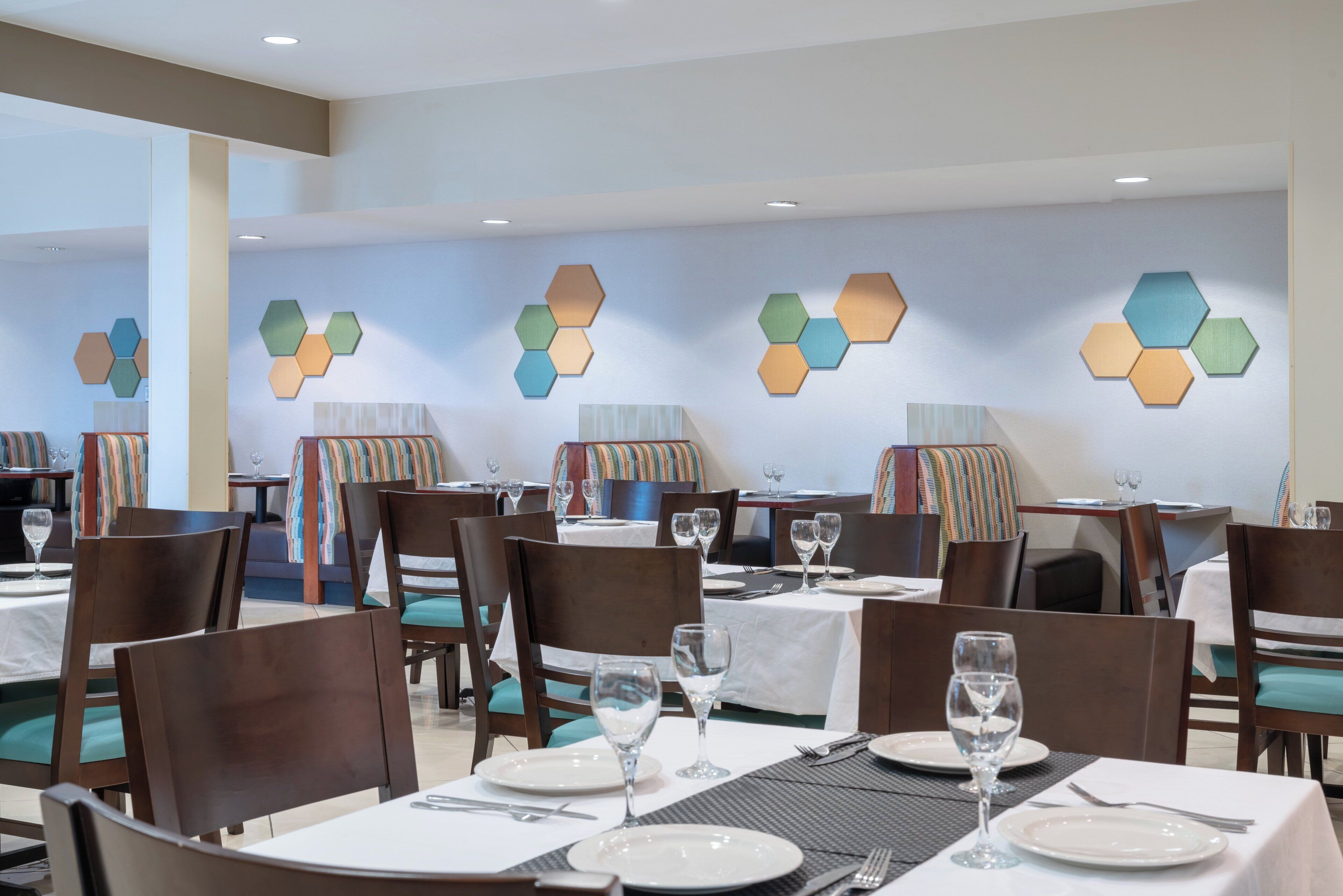 A restaurant with hexagonal wall decorations, wooden chairs, and tables set for dining.