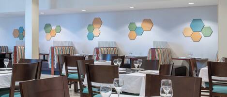 A restaurant with hexagonal wall decorations, wooden chairs, and tables set for dining.