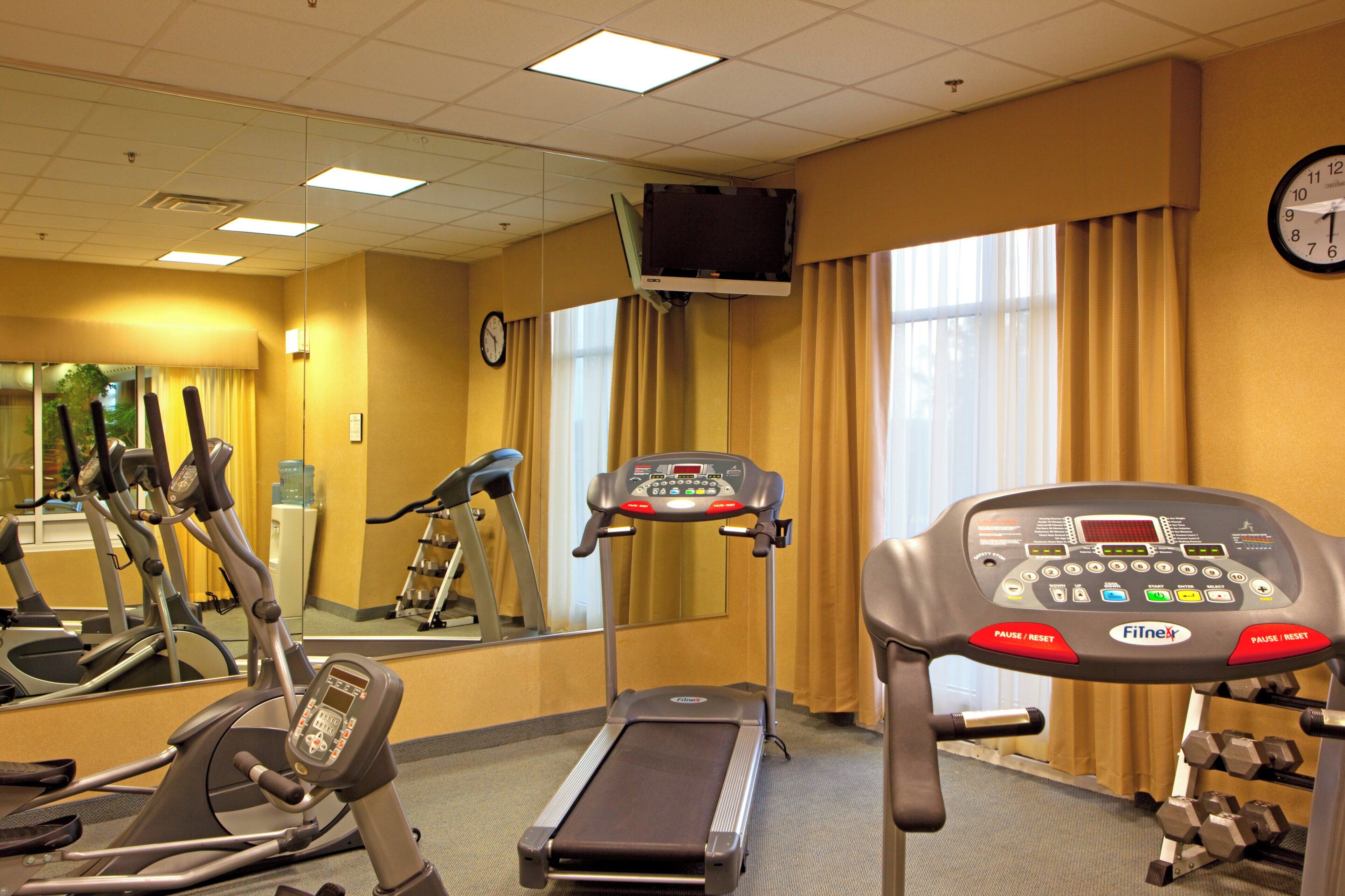 Gimnasio de hotel con cintas de correr, elípticas y escaladora.