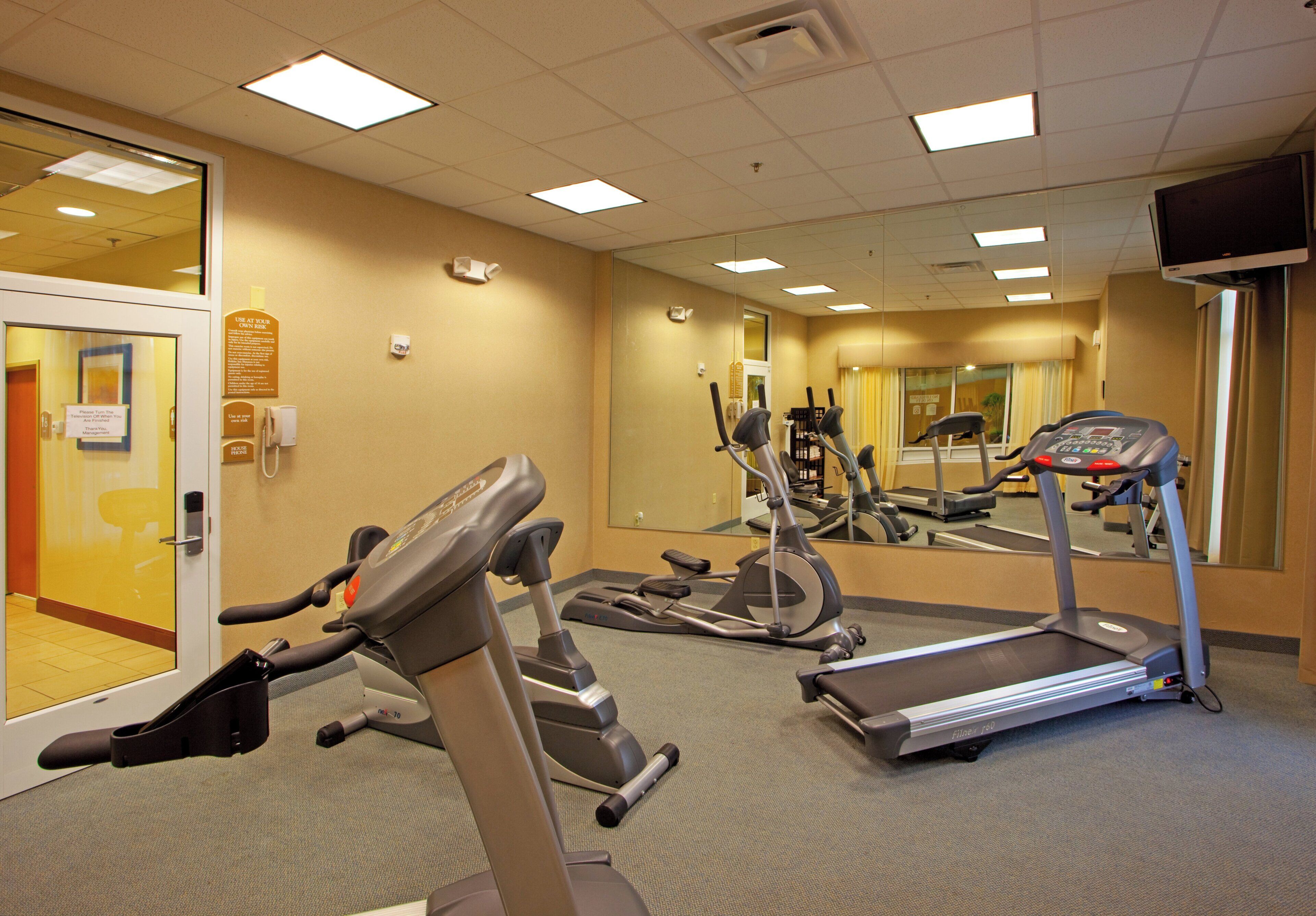 A fitness room with treadmills, elliptical machines, and exercise bikes.