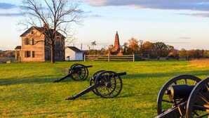 A historic site with cannons, a wooden building, and a church steeple. - Holiday Inn Manassas - Battlefield by IHG (Manassas)