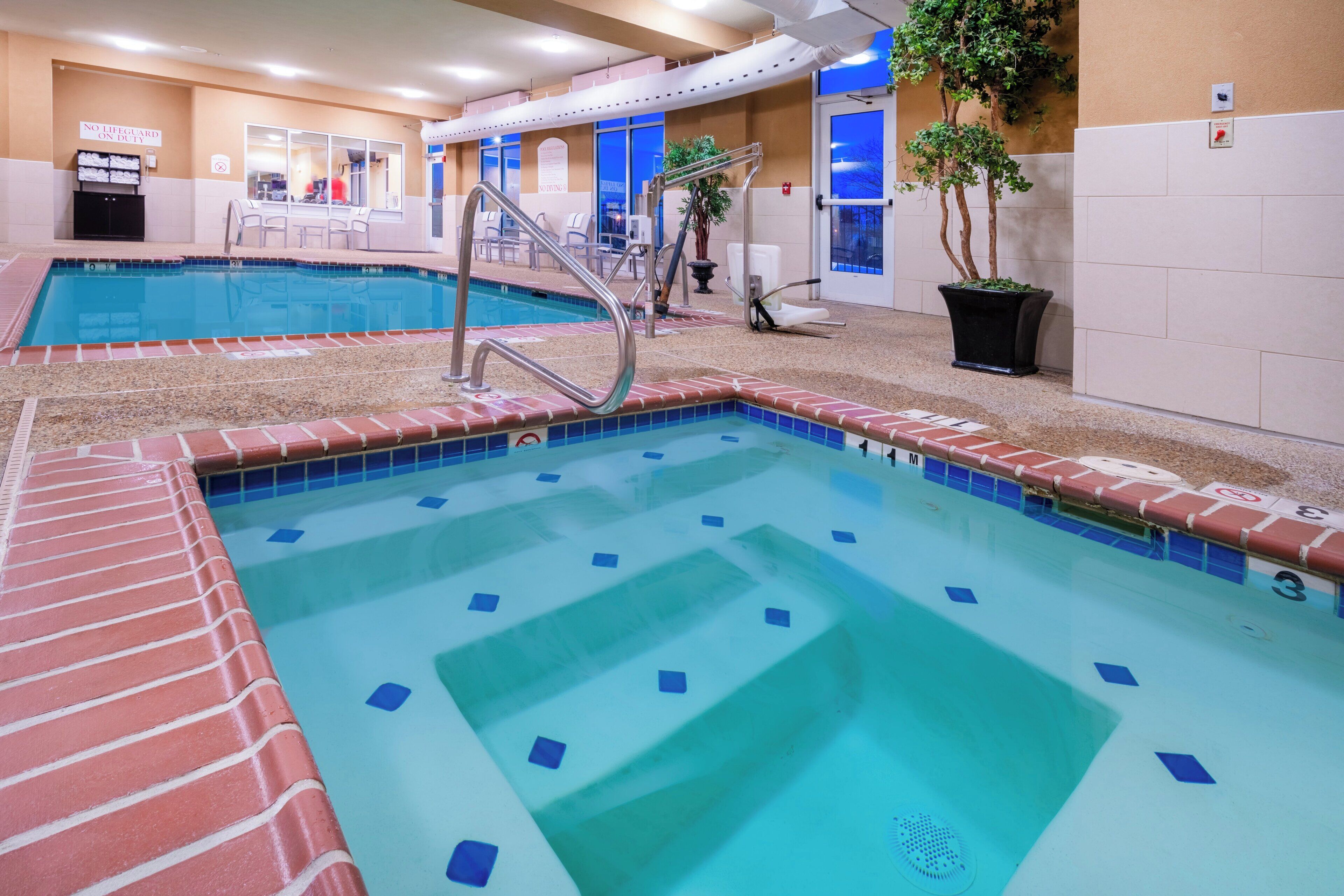 Una piscina con tabla de clavados y sillas de descanso.