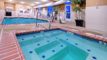 Una piscina con tabla de clavados y sillas de descanso.