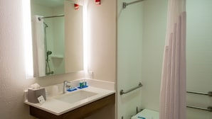 Une salle de bain avec un lavabo blanc, un miroir et un espace douche.