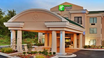 Un bâtiment de l’hôtel Holiday Inn Express & Suites doté d’une entrée couverte et d’un espace jardin aménagé.