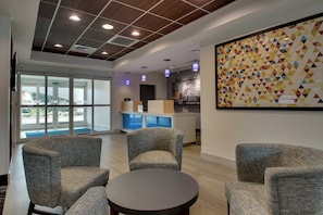 A modern interior with seating, a round table, and a colorful geometric wall art. - Holiday Inn Express & Suites Jacksonville North-Fernandina by IHG (Yulee)