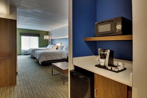 Habitación de hotel con dos camas, microondas, cafetera y una pequeña mesa.