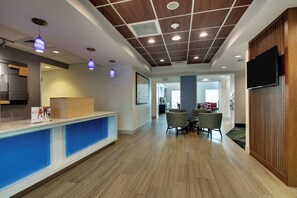 A reception area with a wooden reception desk, blue storage compartments, and a modern ceiling design with recessed lighting. - Holiday Inn Express & Suites Jacksonville North-Fernandina by IHG (Yulee)