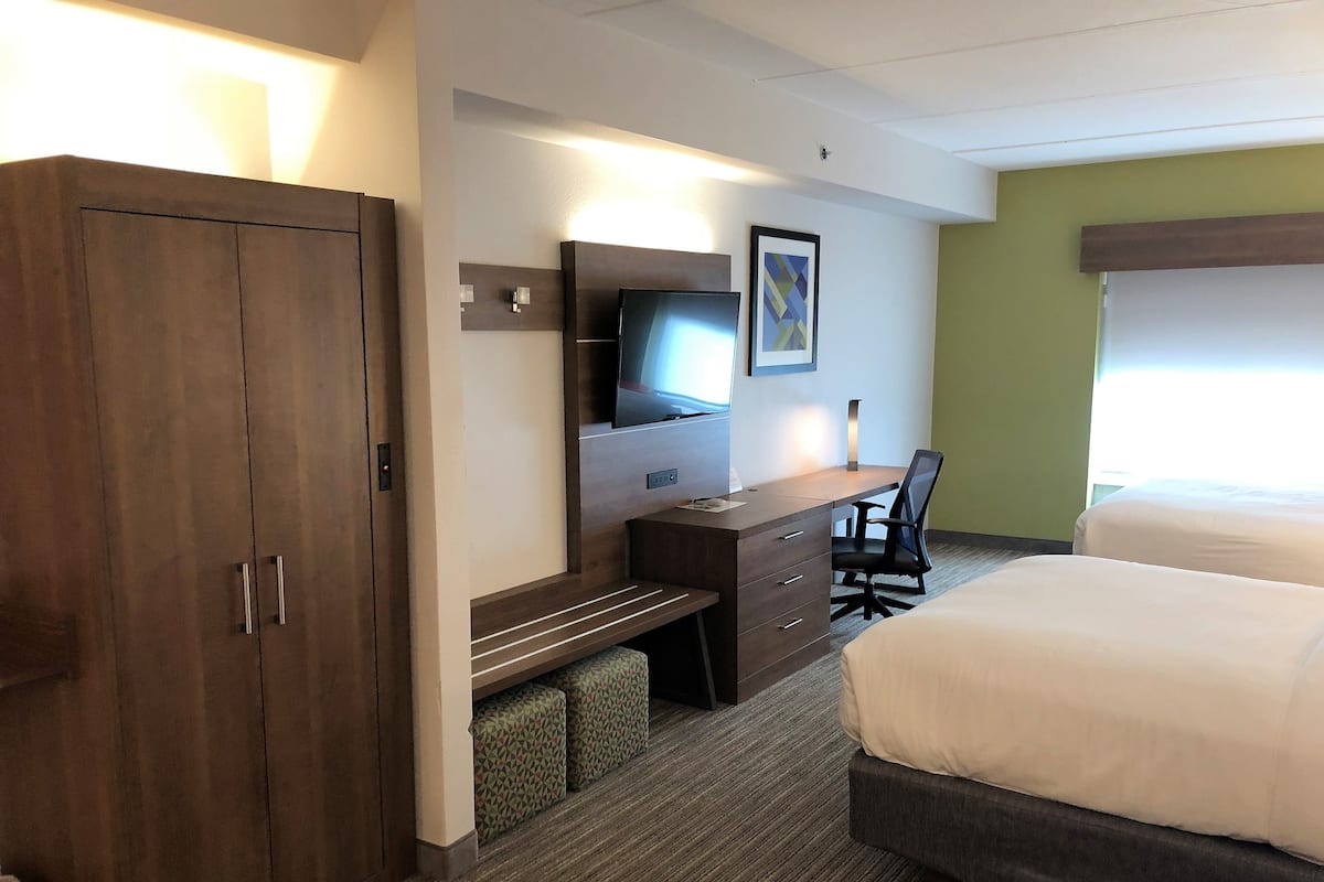 Ein Hotelzimmer mit einem Bett, einem Schreibtisch mit Stuhl, einem Fernseher und einem Kleiderschrank.